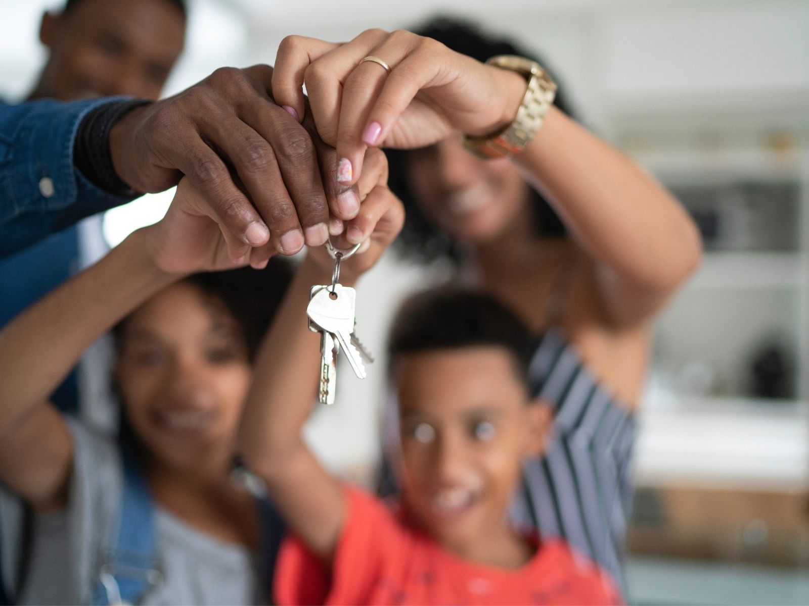 Family of four lifting house keys together in their new home