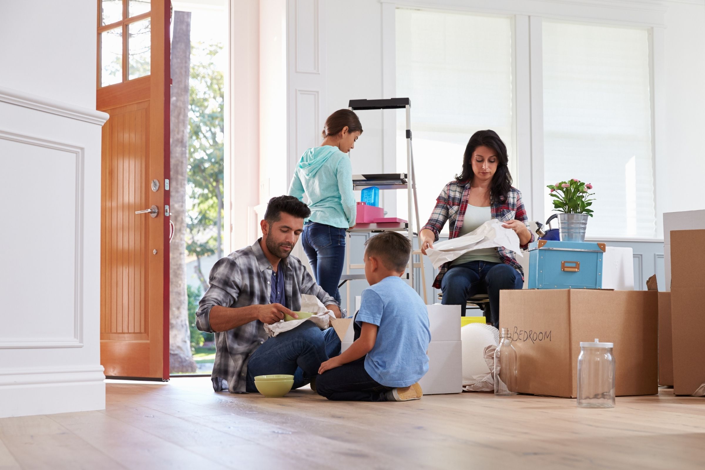 Family unpacking boxes in their new home, child playing on the floor